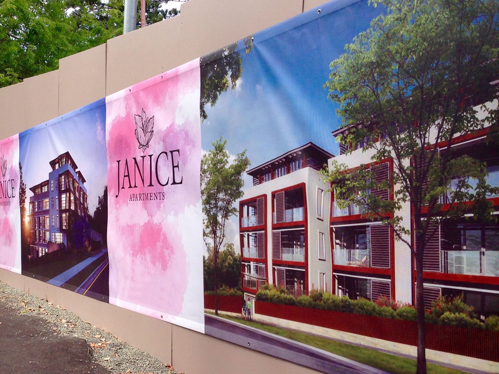 Full-colour mesh banner displaying architectural renderings of Janice Apartments, featuring modern building designs with greenery and artistic branding elements.