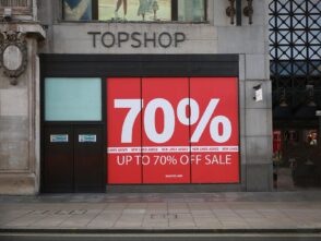 Vinyl banner display advertising "UP TO 70% OFF SALE" at Topshop storefront, highlighting promotional offers in a vibrant red and white design.
